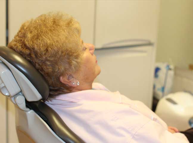 Older woman sitting in the dental chair under dental sedation.