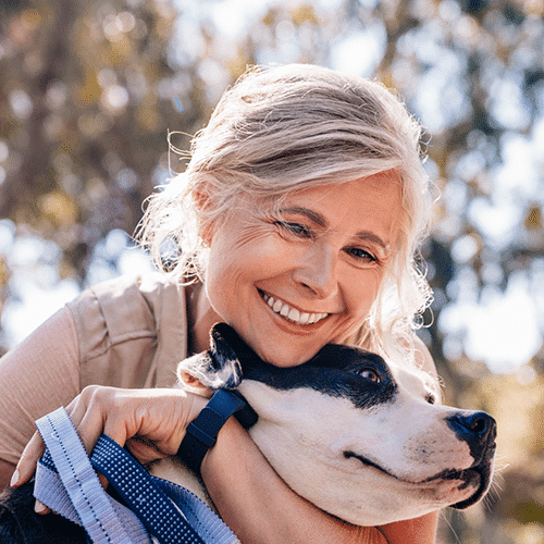 Older woman cuddling her dog and smiling